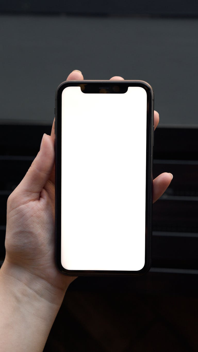 Close-up of a hand holding a smartphone with a blank screen, ideal for mockup use.