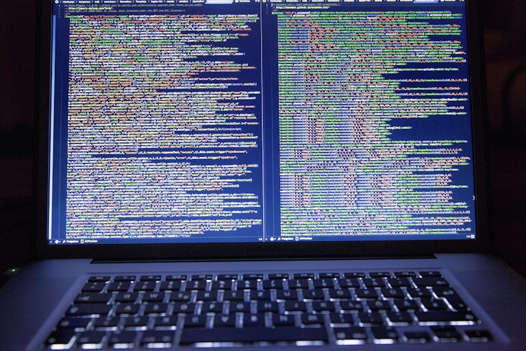 Laptop displaying source code with dual screens for software development.