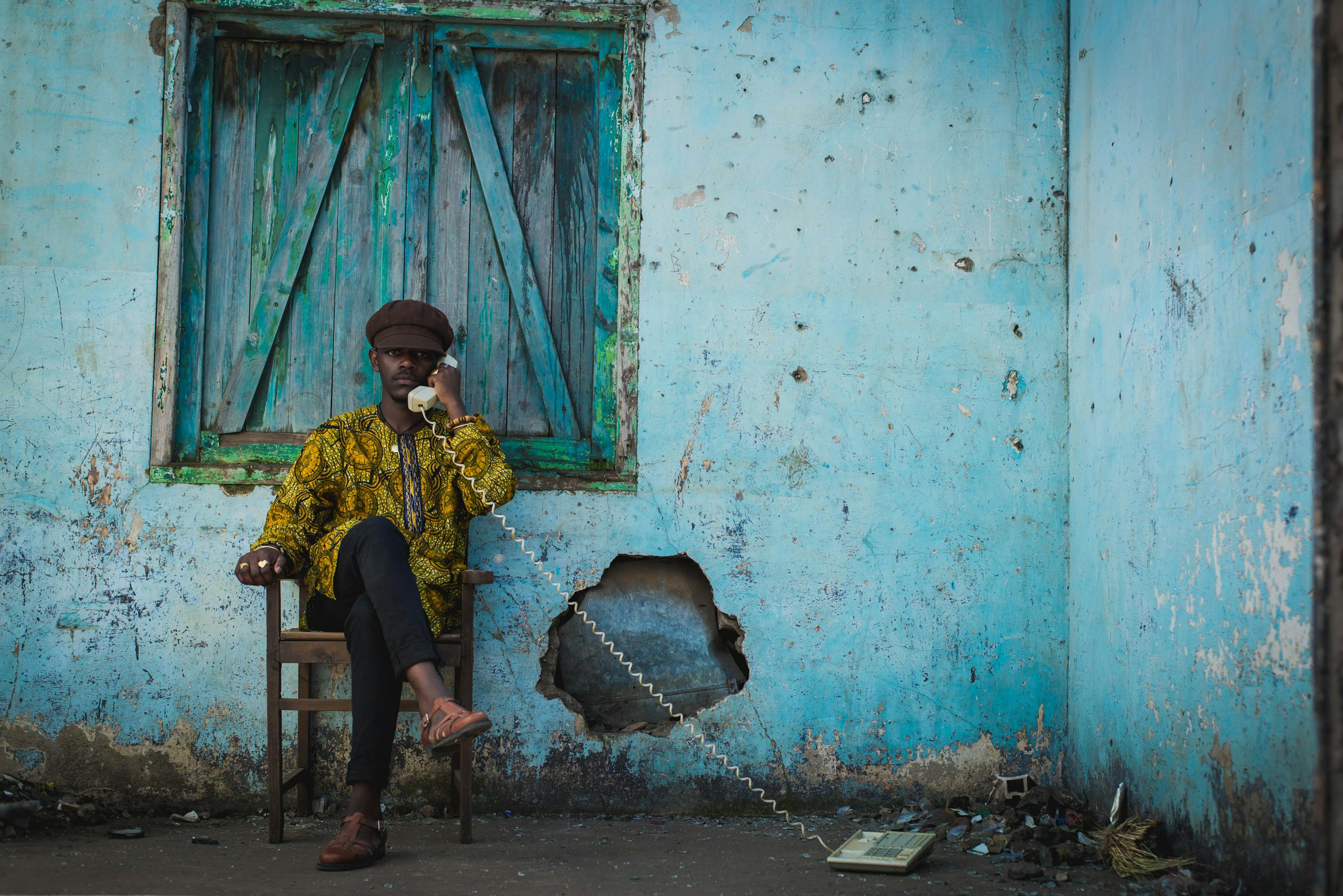 Portrait of a man on a phone in a vintage setting with worn walls and window.